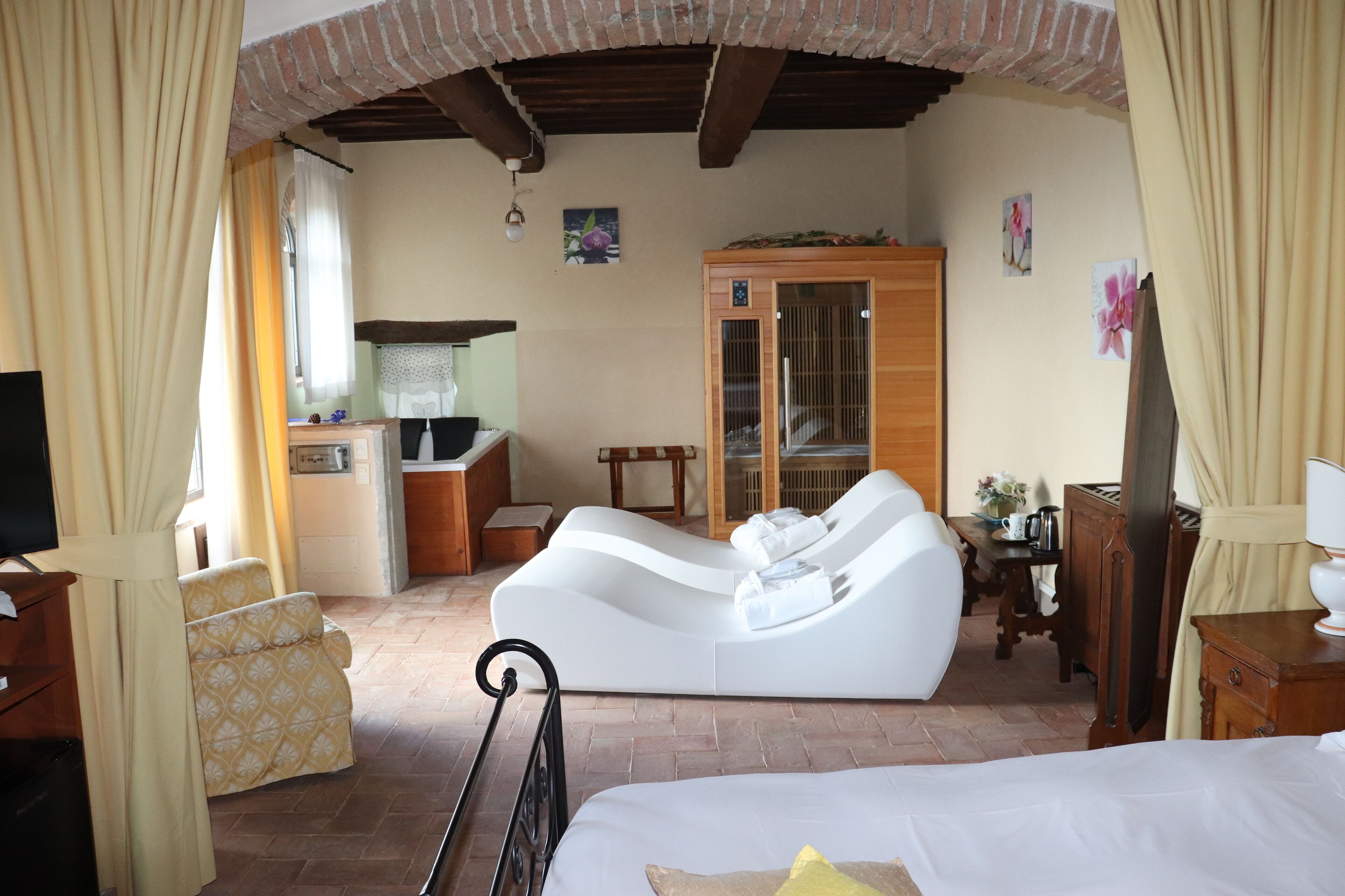 A room with a bed, a white sofa, a wooden cabinet, and a television.