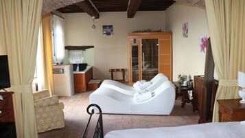 A room with a bed, a white sofa, a wooden cabinet, and a television.