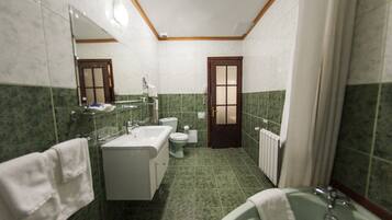 Un baño con bañera, lavabo, inodoro y espejo.