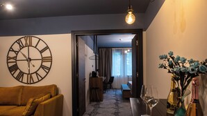 A living room with a large wall clock, a sofa, a coffee table, and a dining area in the background. - Bucharest Comfort Suites (Bucharest)