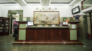 A reception desk with a framed landscape painting above it, a computer monitor, and a telephone. - Bucharest Comfort Suites (Bucharest)