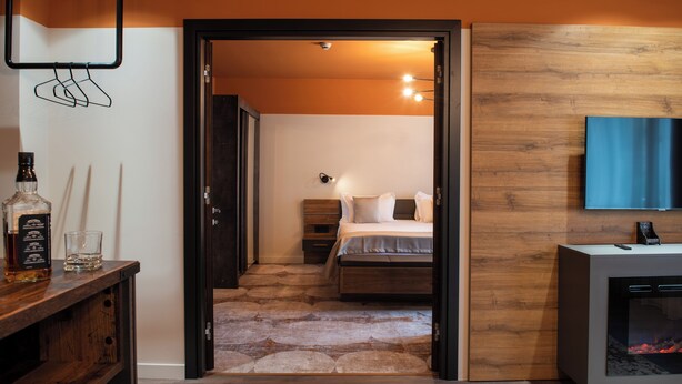 A hotel room with a bed, bedside table, and a fireplace. - Bucharest Comfort Suites (Bucharest)