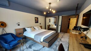 A modern bedroom with a bed, a blue armchair, a desk, and a mirror. - Bucharest Comfort Suites (Bucharest)
