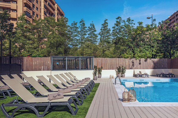 Un espace aménagé au bord de la piscine, avec des chaises longues et une petite piscine.