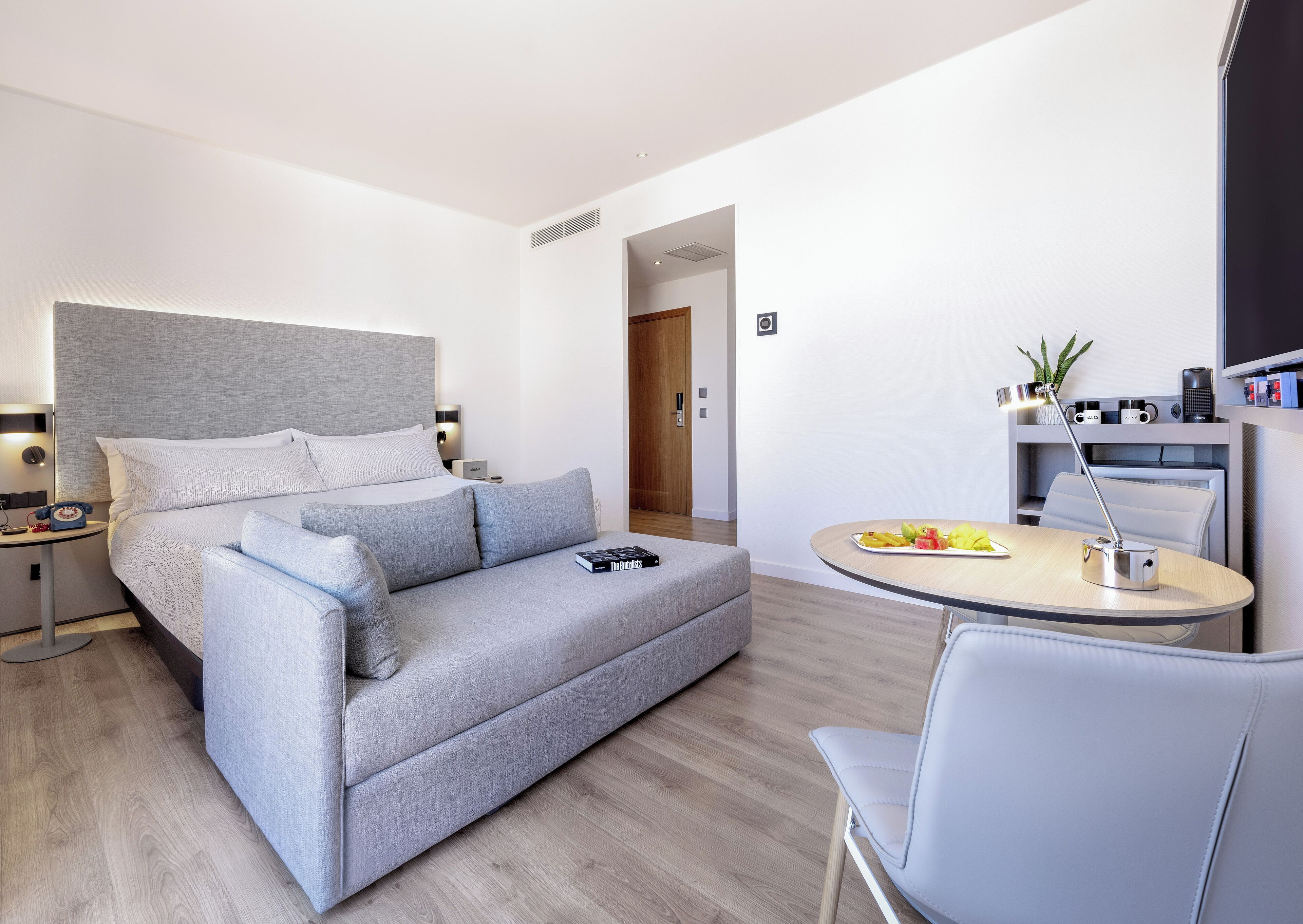 Ett modernt hotellrum med en säng, en soffa, ett skrivbord och en stol.