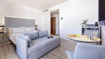 Ett modernt hotellrum med en säng, en soffa, ett skrivbord och en stol.