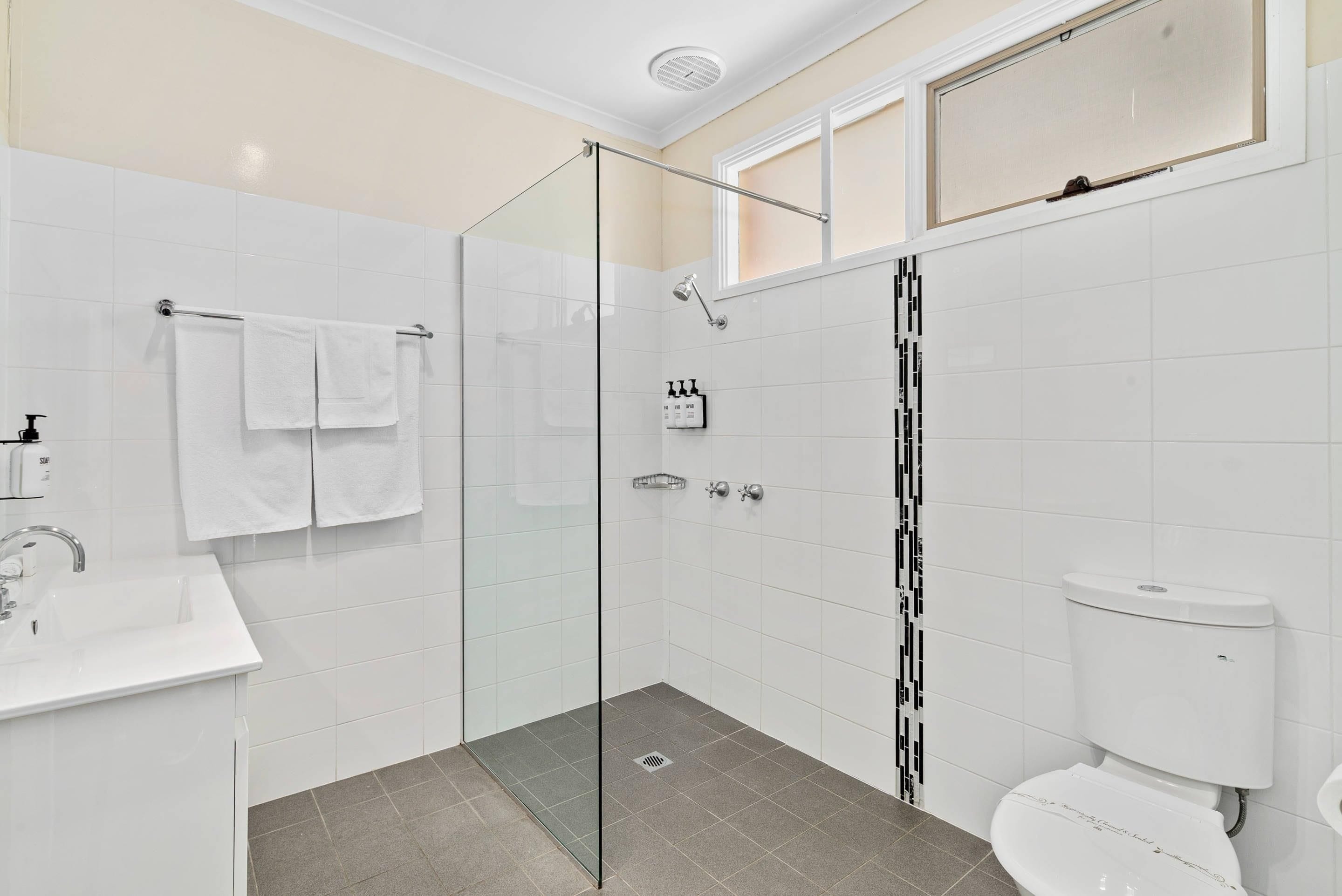 A modern bathroom with a glass-enclosed shower, a white sink, and a toilet.
