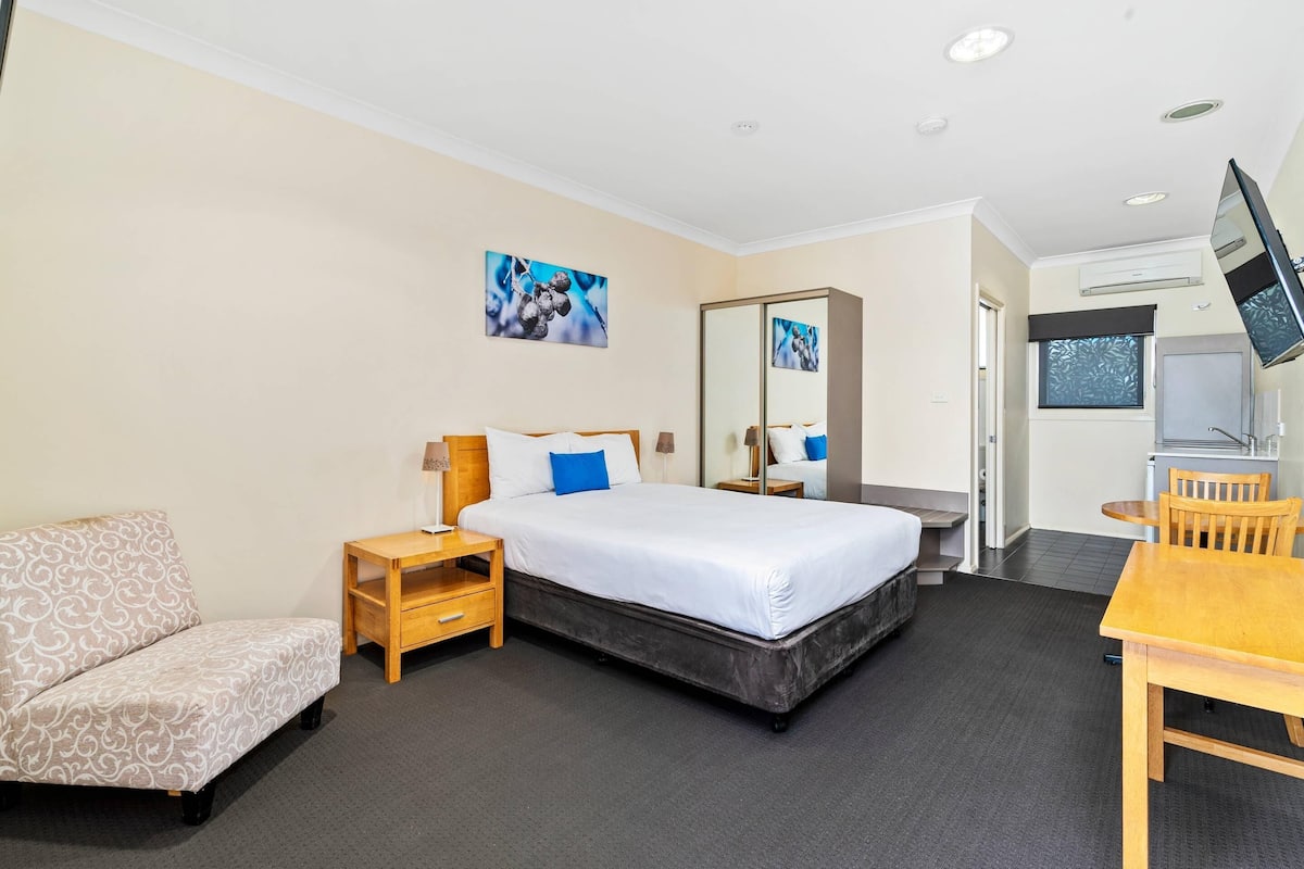 A hotel room with a bed, a sofa, a desk, and a TV.