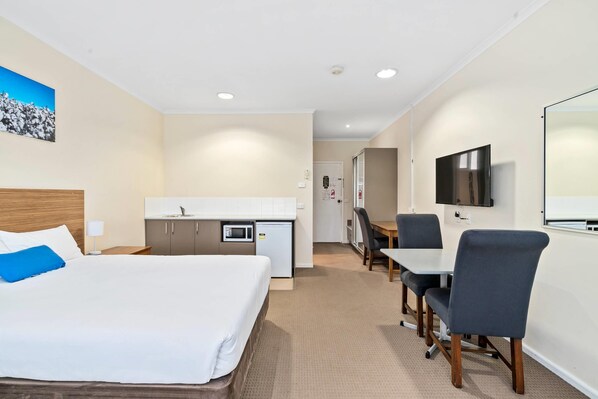 A hotel room with a bed, a desk, a microwave, a TV, and a small kitchenette. - Comfort Inn Bishops Lodge (Hay South)