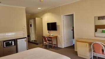 Una habitación de hotel con cama, escritorio, silla, televisor y un minibar.