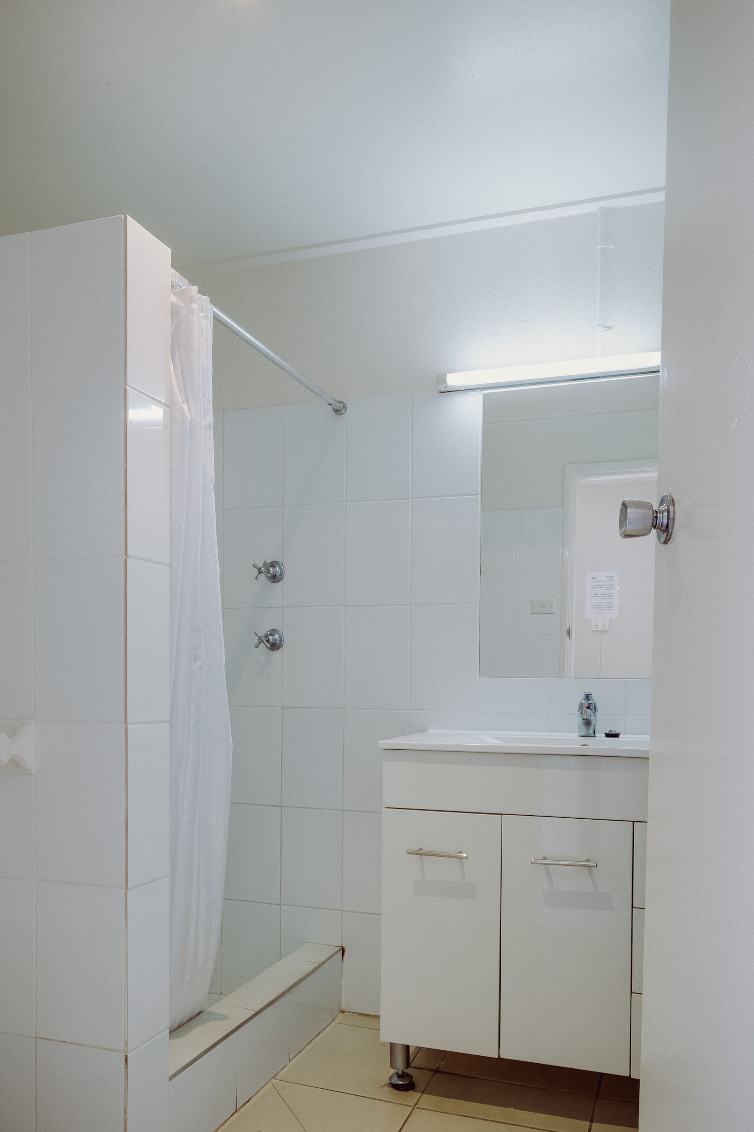 A bathroom with a shower, a sink, and a mirror.