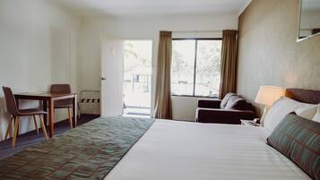 Een hotelkamer met een bed, een bureau, een stoel, een bank en een raam met gordijnen.