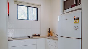 A kitchen with white cabinets, a microwave, and a refrigerator. - Artesian Spa Motel (Moree)