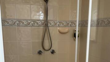 A glass-enclosed shower area with beige tiles and a decorative border.