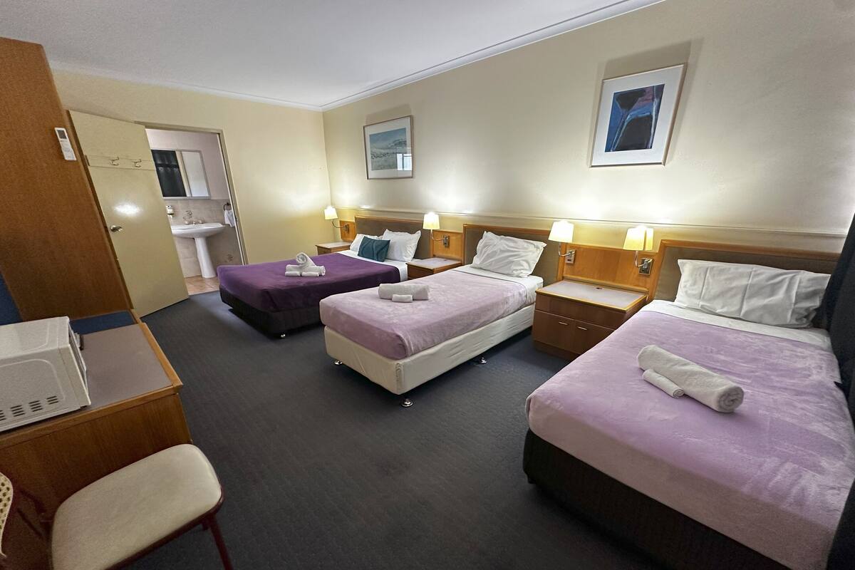 Une chambre d’hôtel avec deux lits, un bureau, une chaise et une petite kitchenette.