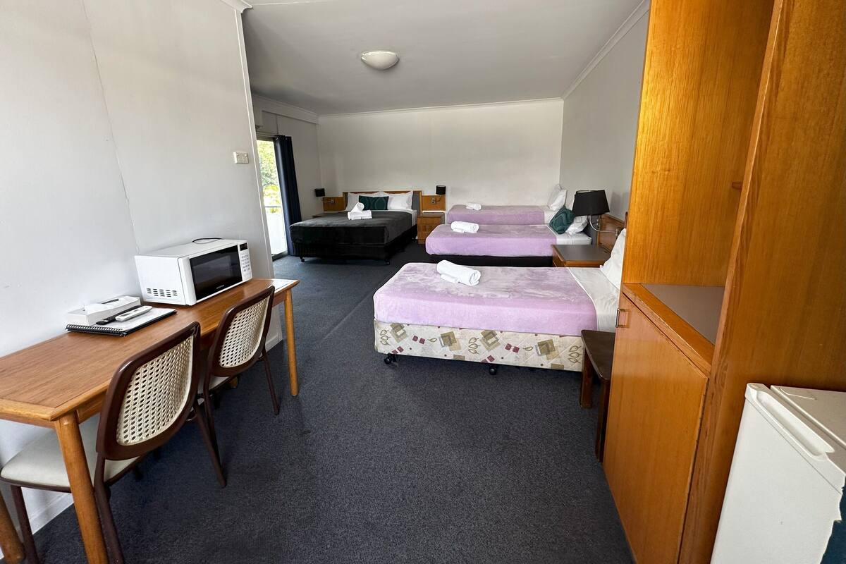 Une chambre d’hôtel avec deux lits, un bureau avec un ordinateur, un four à micro-ondes et une chaise.