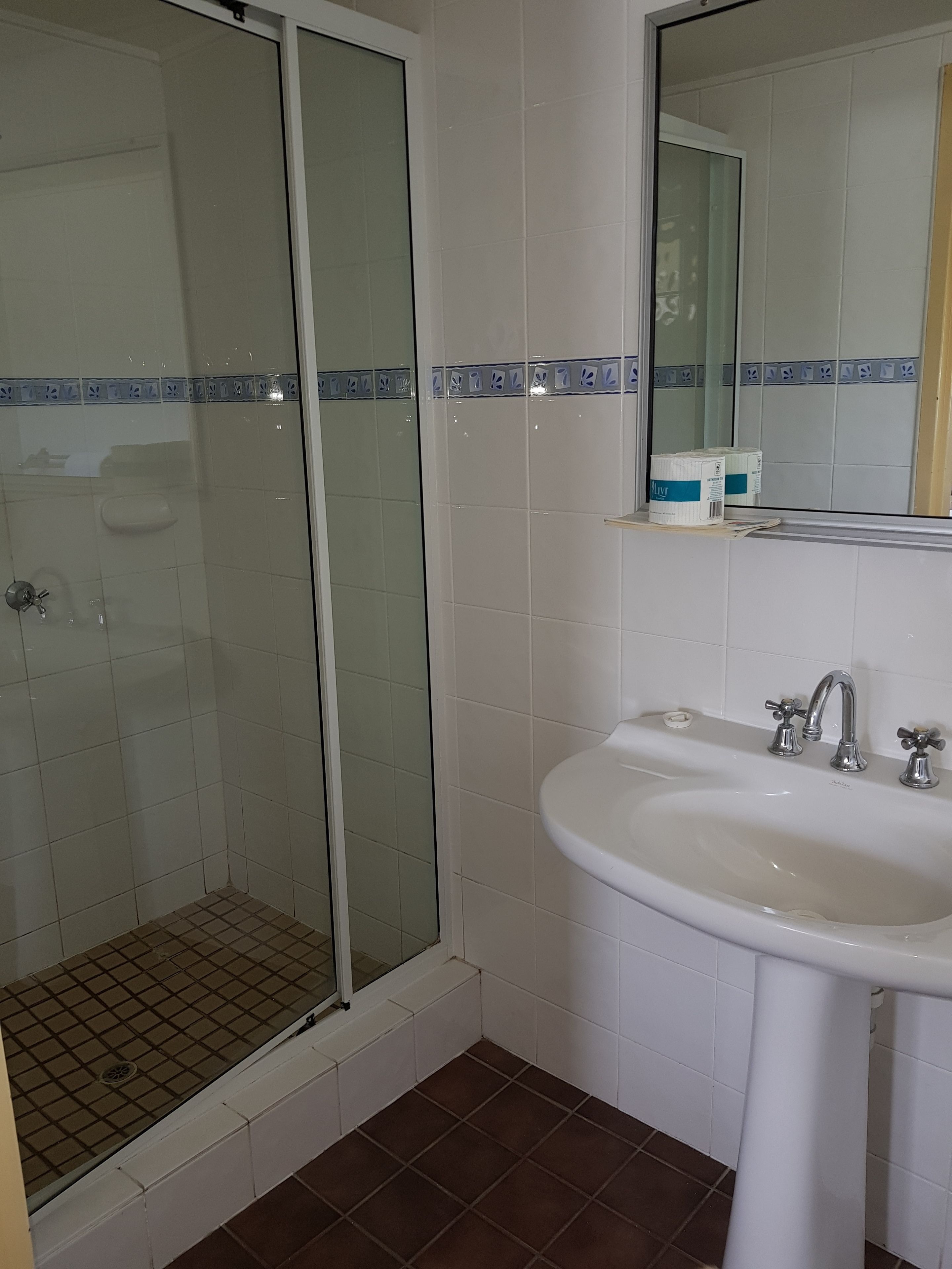 Een badkamer met een douchecabine van glas, een wit wastafelmeubel en een spiegel erboven.