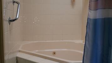 Un baño con bañera, cortina de ducha y barra de apoyo.