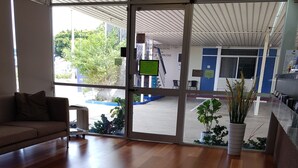 A spacious room with a wooden floor, a sofa, and a large window with a view of the outside. - The Q Motel (Allenstown)