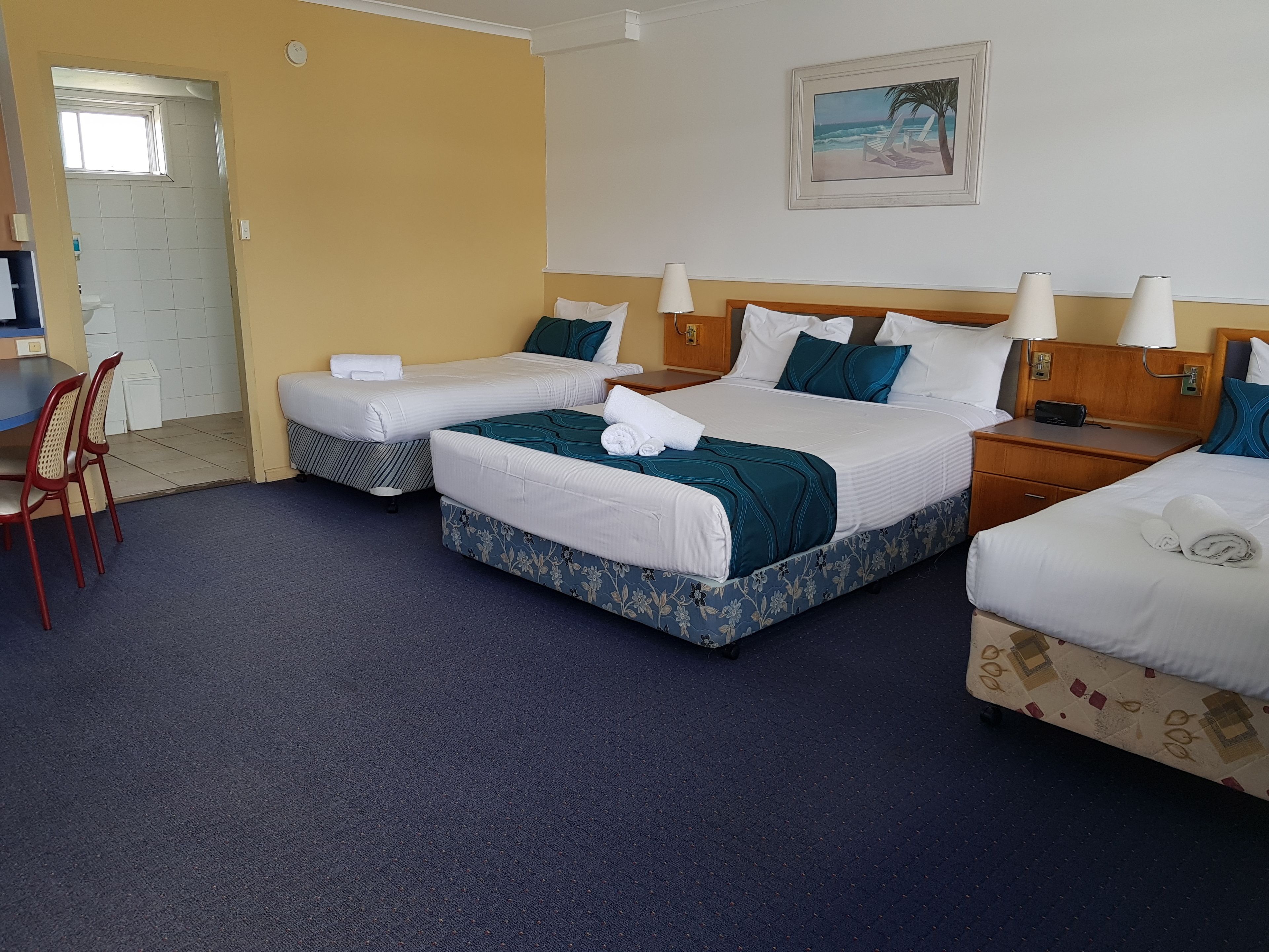 A hotel room with two beds, a desk, and a chair.