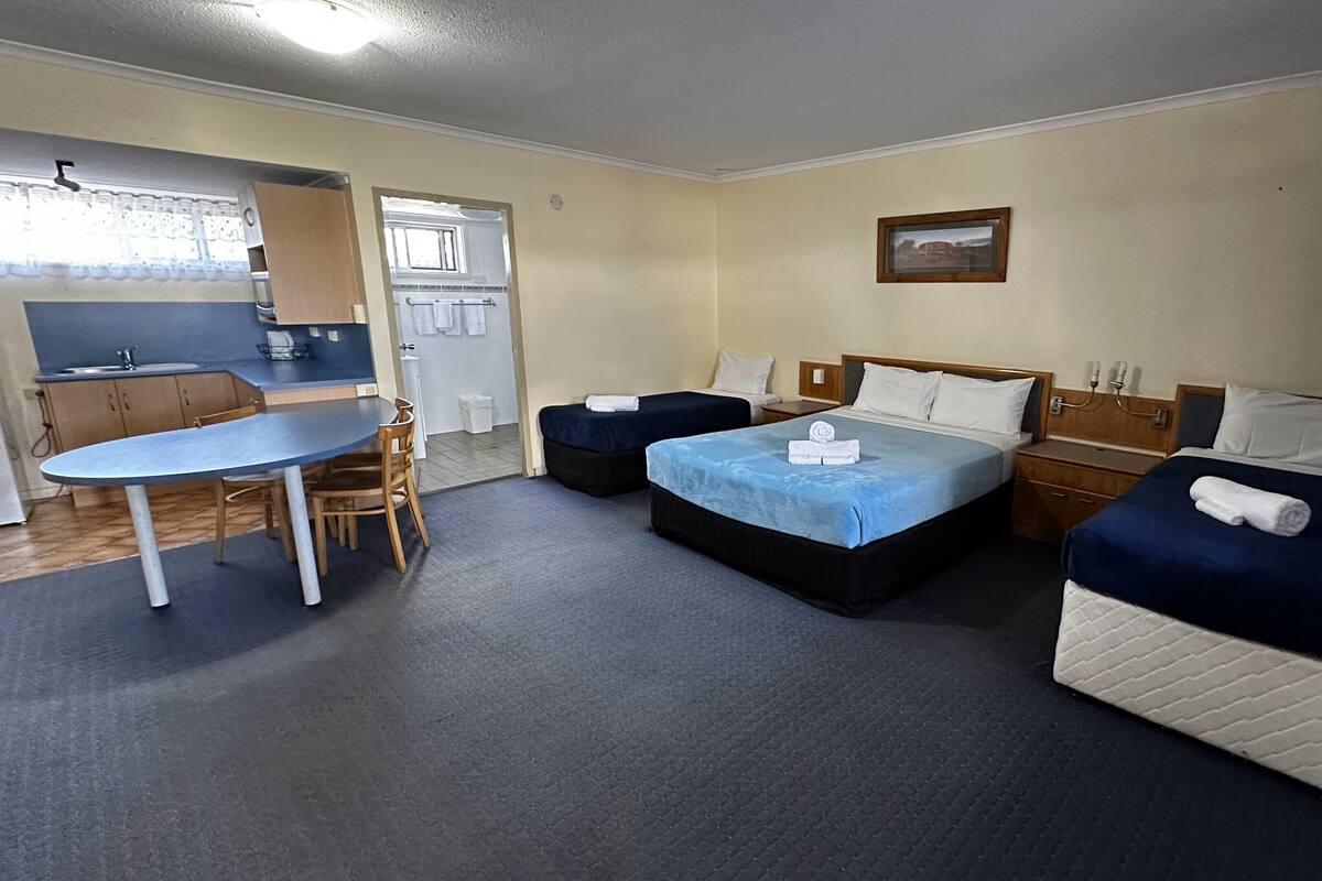 Une chambre d’hôtel avec deux lits, une petite table et une kitchenette.
