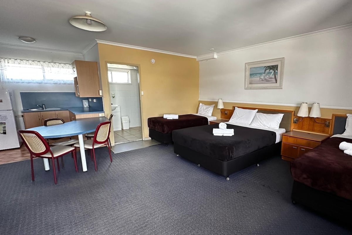 Une chambre d’hôtel avec deux lits, un bureau et une kitchenette.