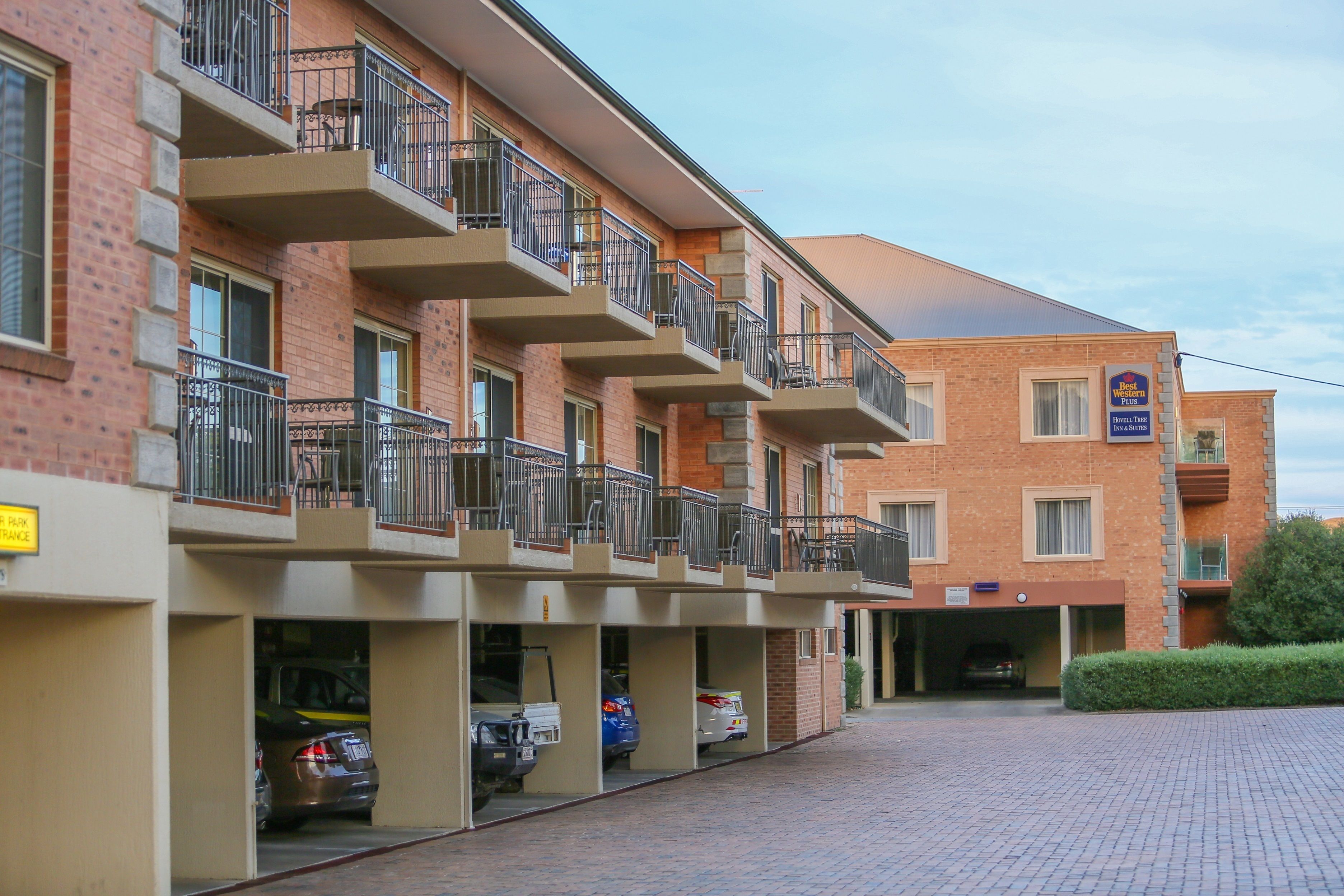 A multi-story brick building with balconies, a parking garage, and a sign indicating a hotel.