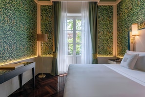 A hotel room with a large bed, a desk, a lamp, and a window with curtains. - Palazzo Excelsior - The Leading Hotels of the World (Palermo)