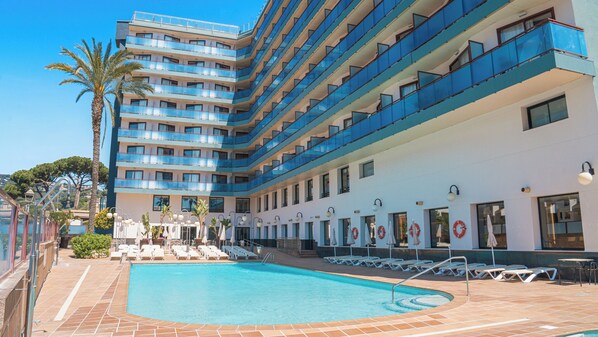 A hotel with a pool, multiple balconies, and sun loungers. - htop Jadhe (Calella)