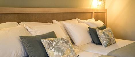 A hotel room with a large bed, multiple pillows, and a wall-mounted light fixture.