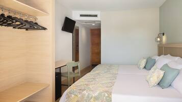 Una habitación de hotel con cama, escritorio, televisor y armario.