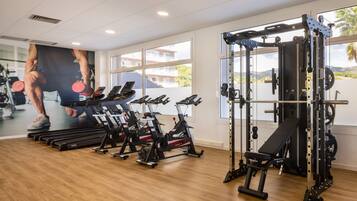A gym with cardio machines, weightlifting equipment, and a large mirror.