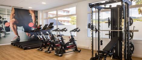 A gym with cardio machines, weightlifting equipment, and a large mirror.