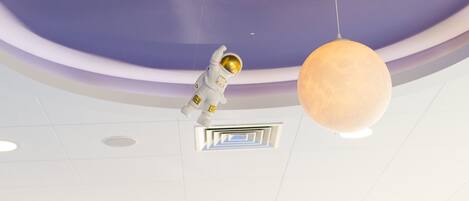 Eine Decke mit einer sphärischen Leuchte und einer figur, die an einen Astronauten erinnert.