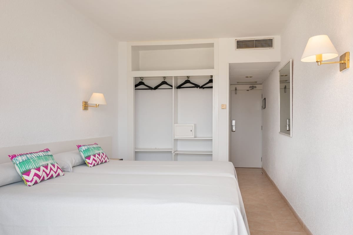 Un dormitorio con una cama, dos almohadas, un armario y un espejo.