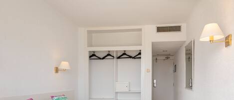 A bedroom with a bed, two pillows, a wardrobe, and a mirror.