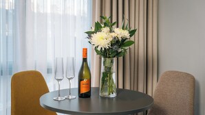 Una mesa redonda con una botella de vino Maschio, dos copas y un florero con flores.