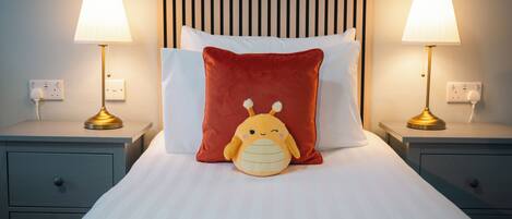 A neatly made bed with a plush toy and two bedside lamps.