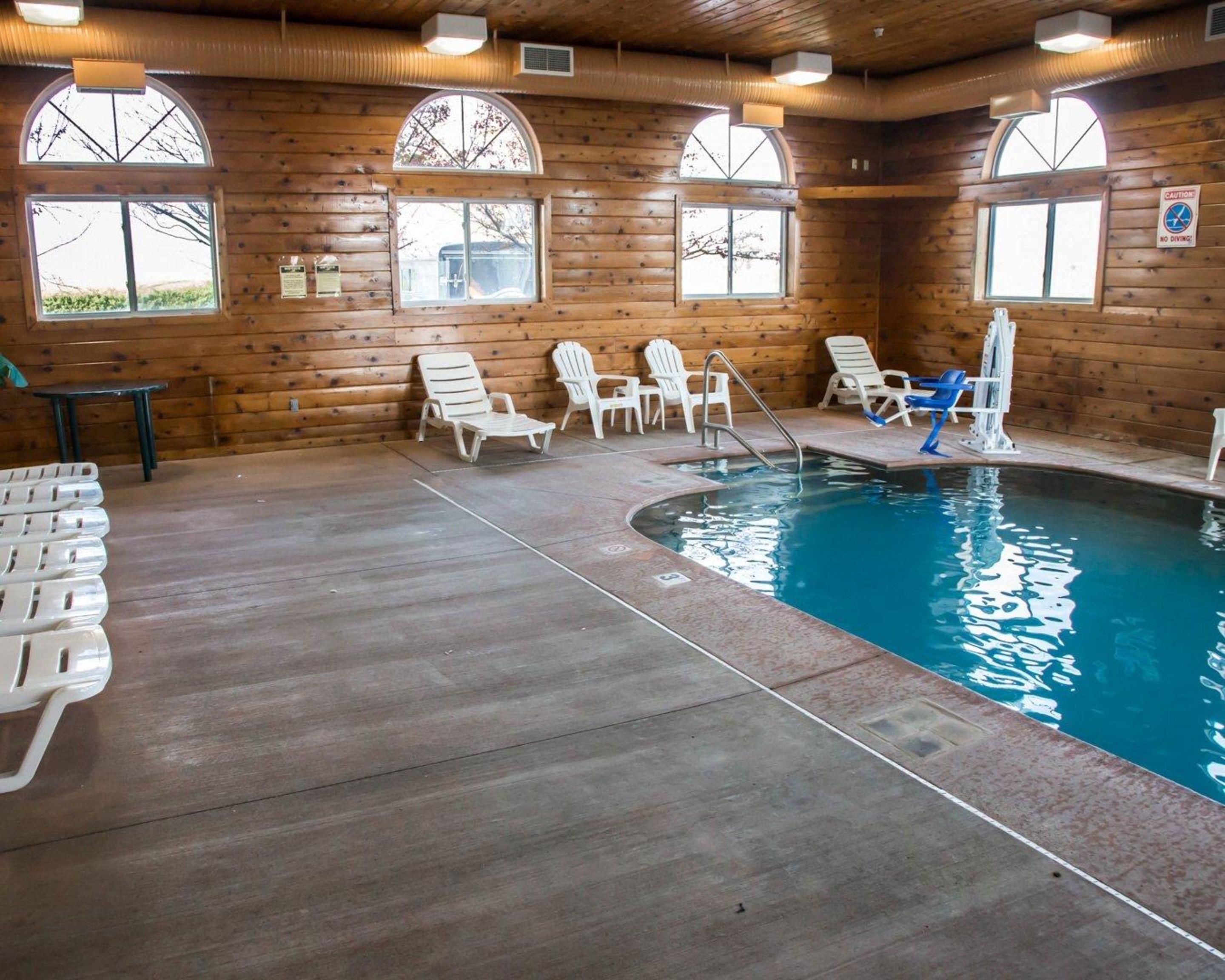 A wooden cabin with a pool, lounge chairs, and a table.