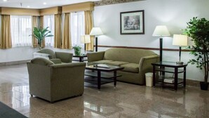 A well-lit living room with a sofa, armchairs, a coffee table, and two lamps. - Quality Inn & Suites Loves Park near Rockford (Loves Park)