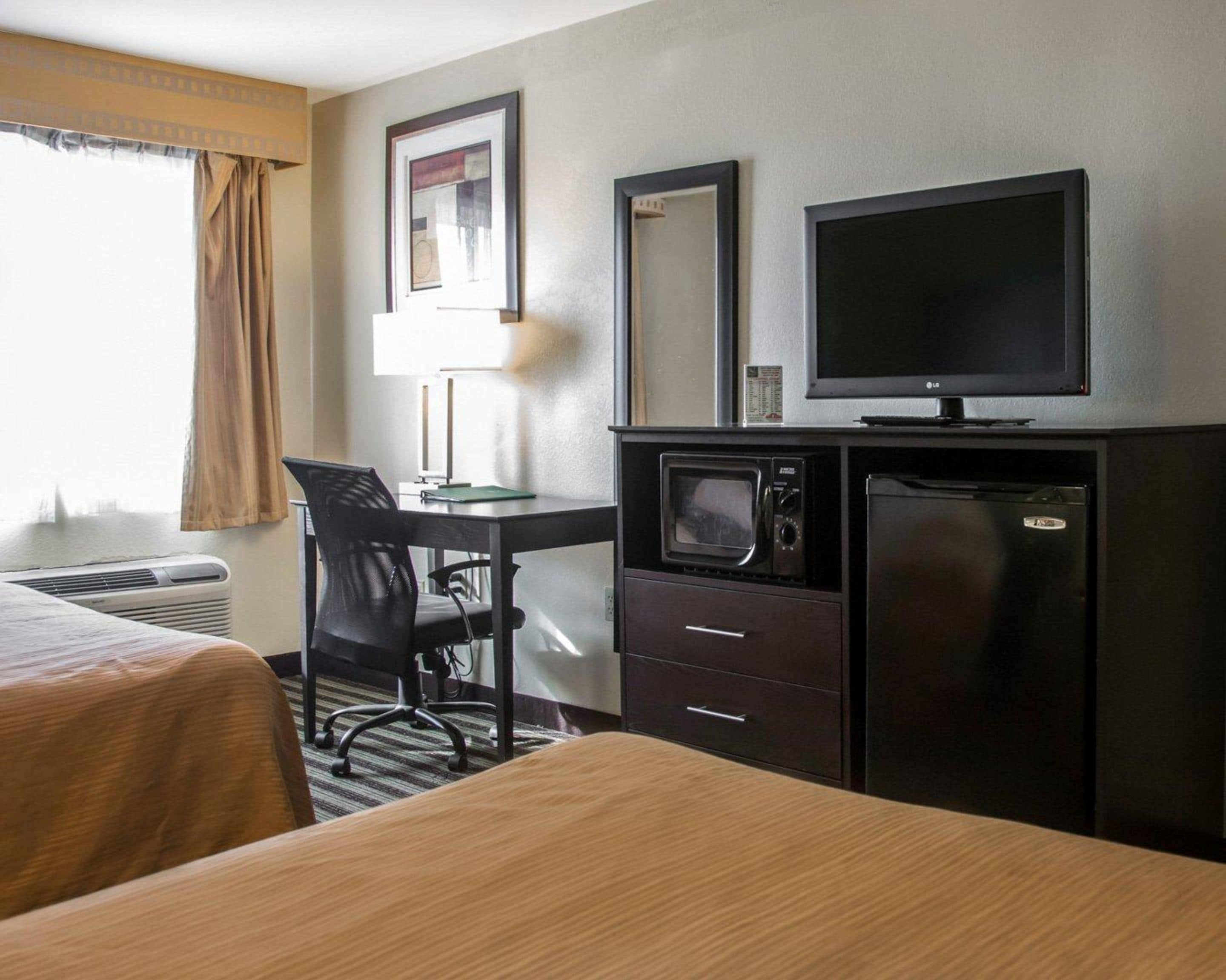 Une chambre d’hôtel équipée d’un lit, d’un bureau avec une chaise, d’une télévision, d’un four à micro-ondes et d’un réfrigérateur.