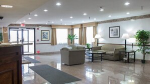 A hotel lobby with a reception desk, seating area, and a green carpet with the hotel name. - Quality Inn & Suites Loves Park near Rockford (Loves Park)
