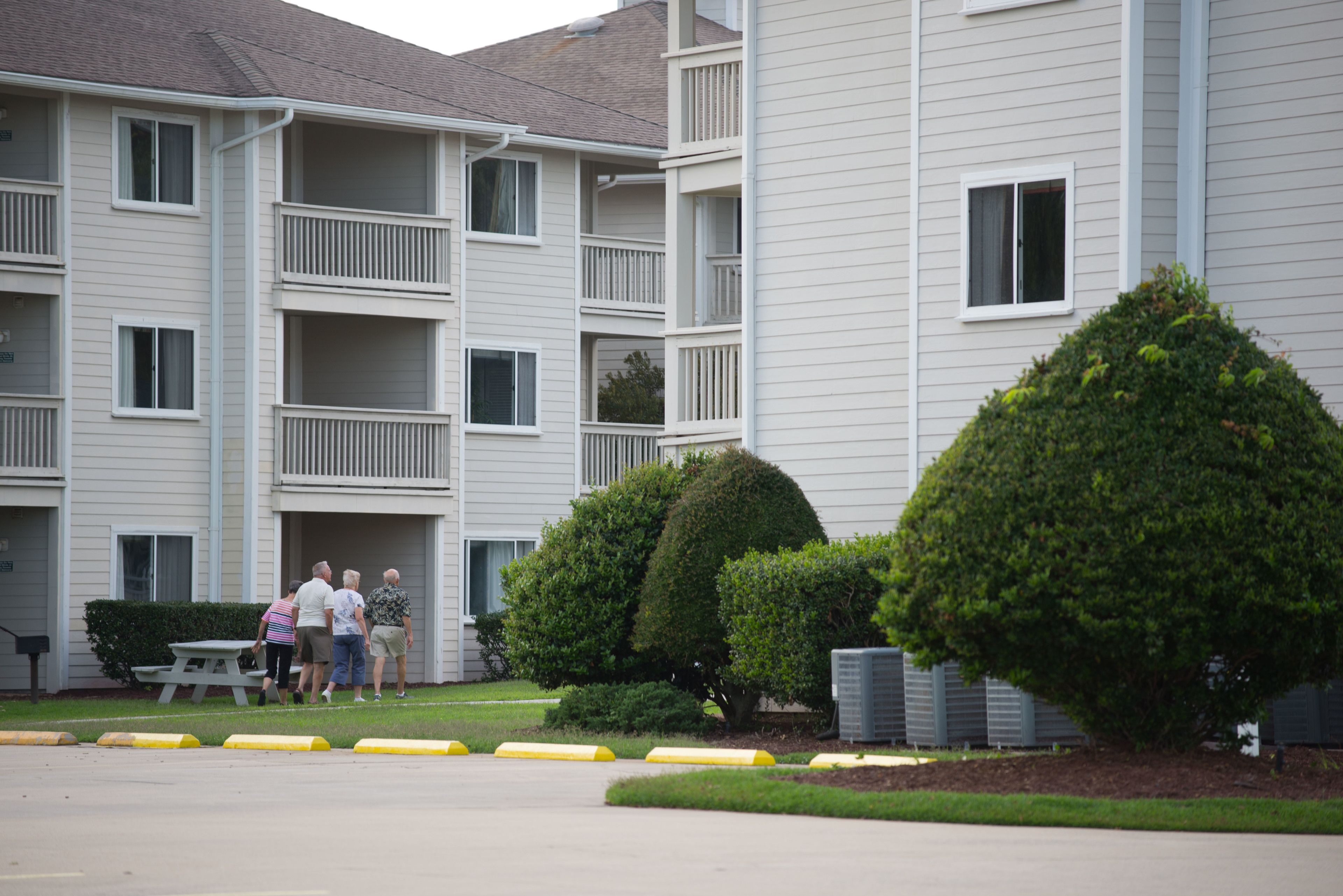 A multi-story residential building with balconies, a picnic table, and well-maintained landscaping.