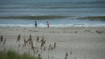 Une plage où se trouvent deux personnes près du bord de l’eau.