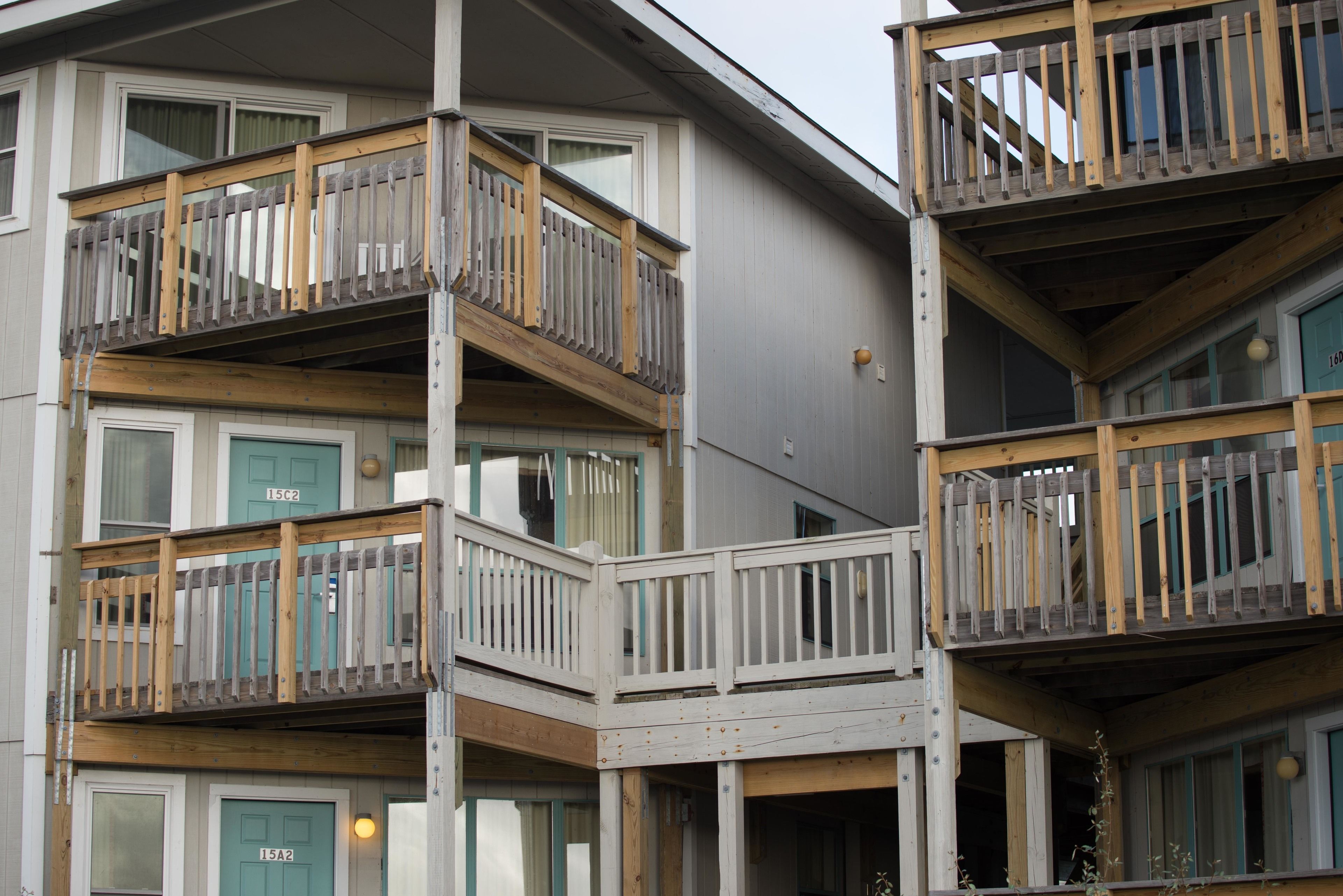 A multi-story residential building with balconies, wooden railings, and doors labeled 15A2 and 15C2.