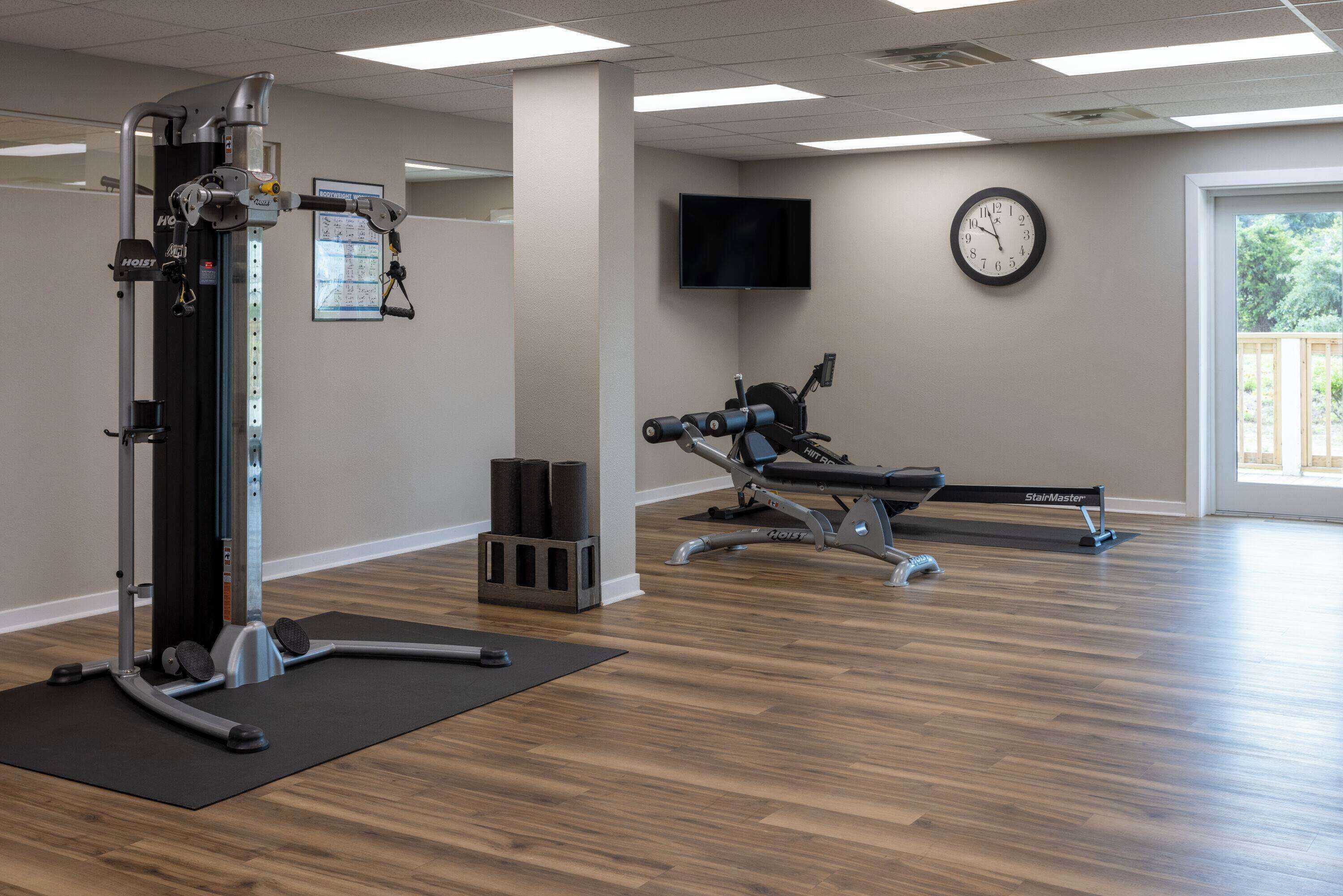 Une salle de sport équipée d’un vélo d’appartement, d’un téléviseur fixé au mur et d’une horloge.