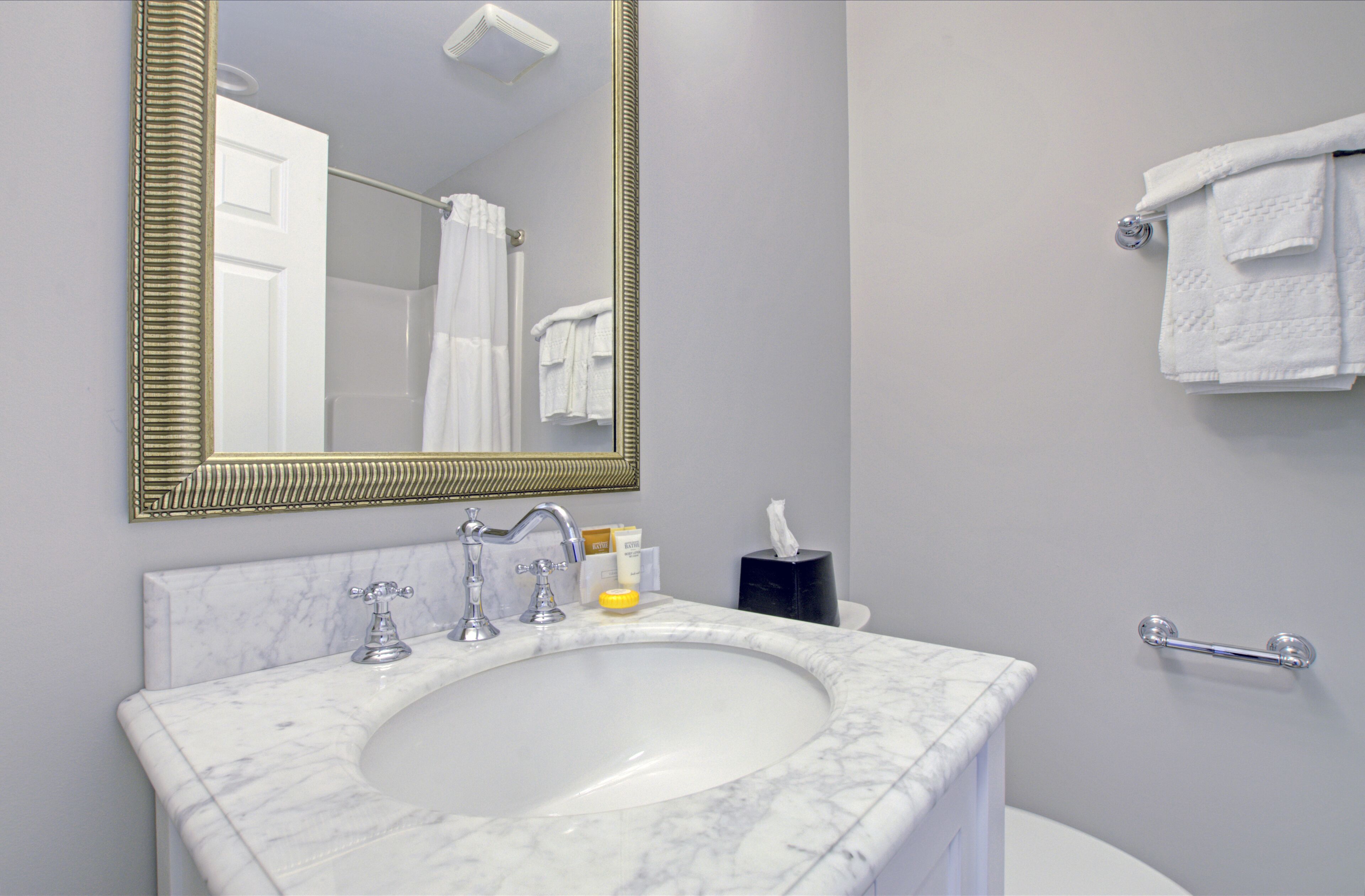 A bathroom with a marble sink, a large mirror, and a towel rack.