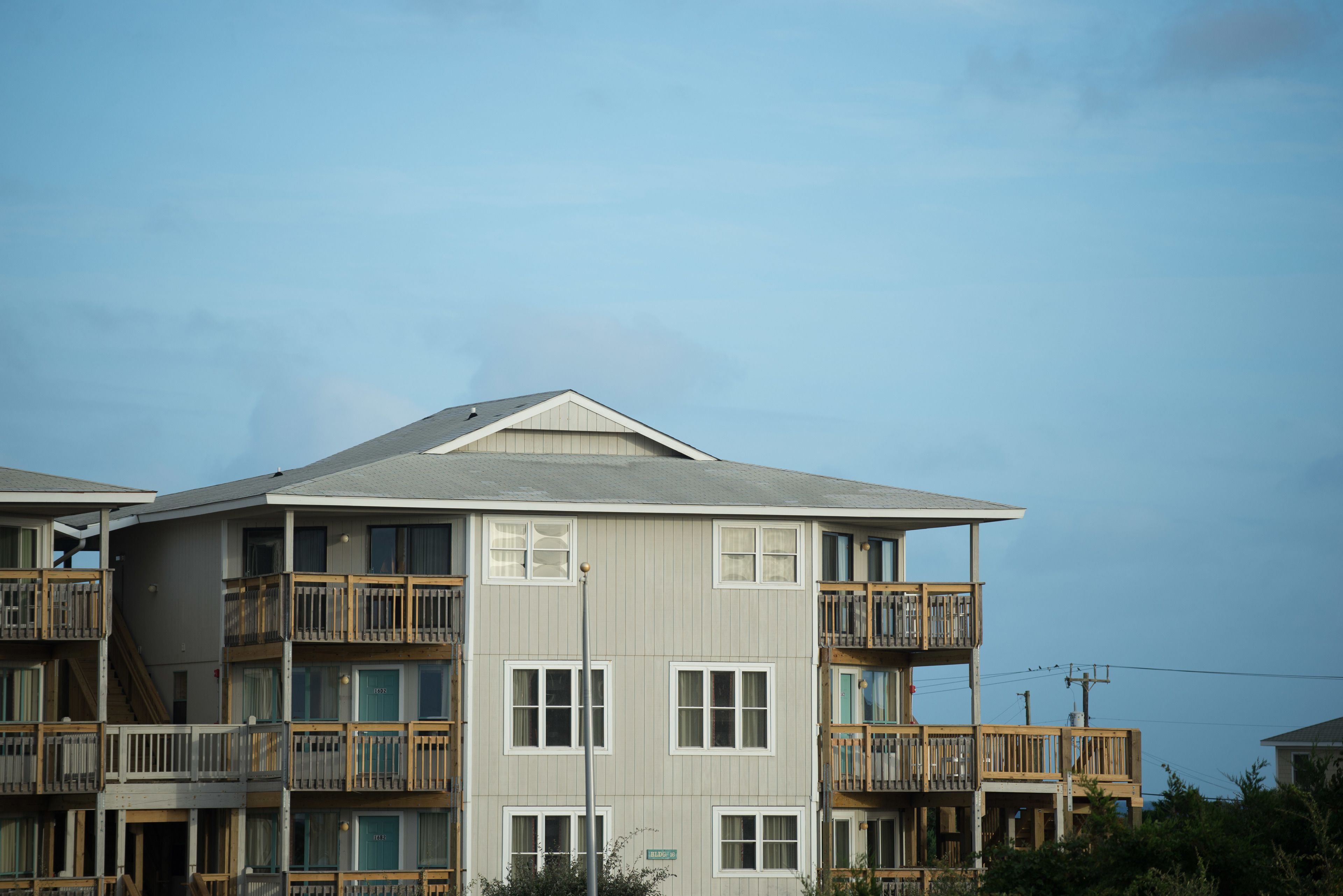 A multi-story residential building with balconies, a flat roof, and a clear sky.