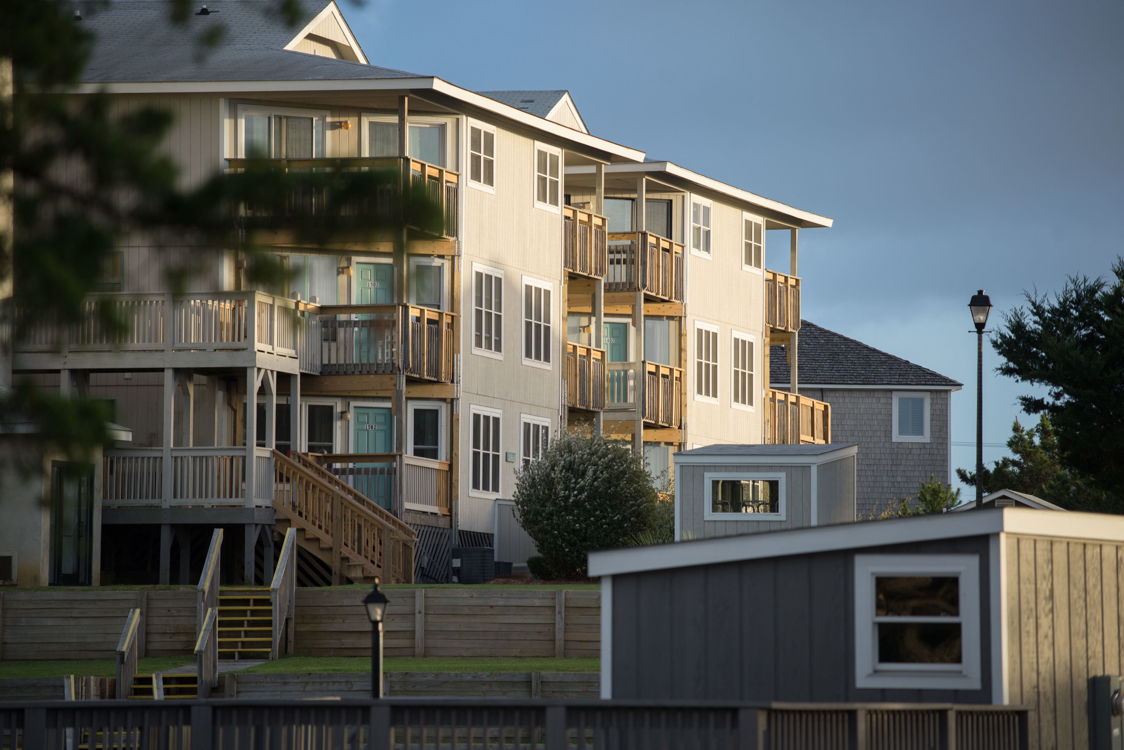 A multi-story residential building with balconies, a small attached garage, and a wooden deck.