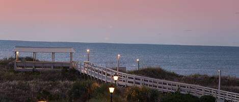 A boardwalk leading to a gazebo by the water at dusk.